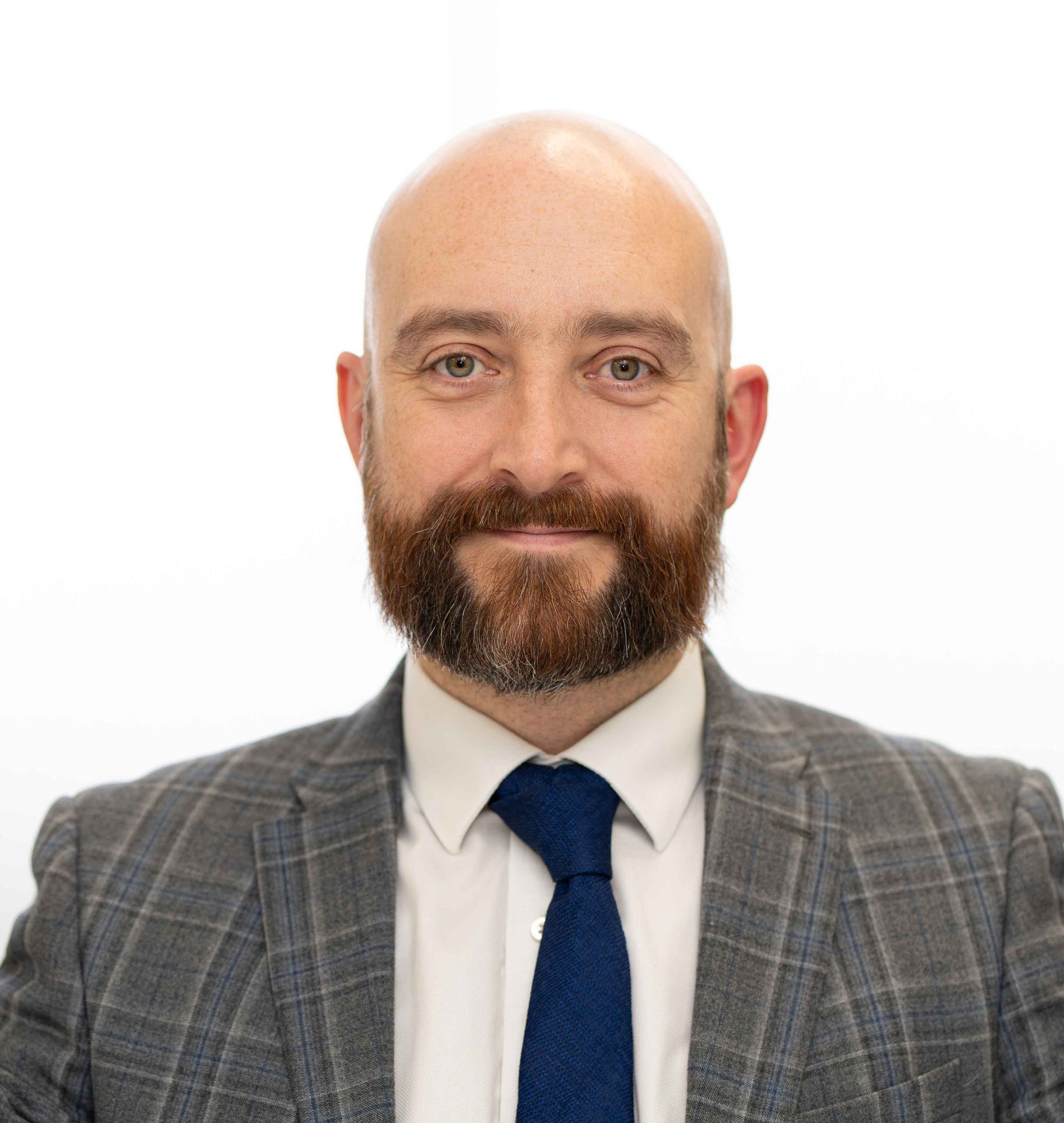 Corporate headshot of a bearded man in a grey suit